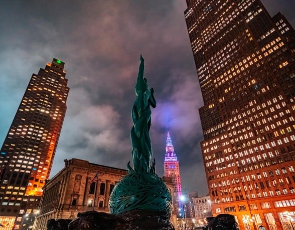 Nighttime city skyline with green statue.