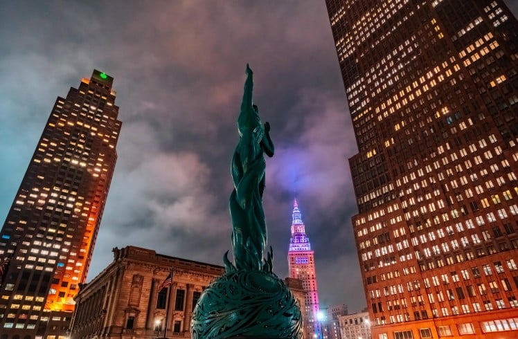 Nighttime city skyline with green statue.