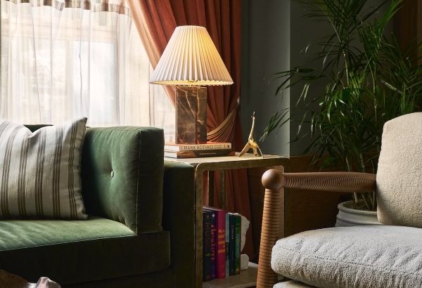 A plush green velvet sofa anchors a richly decorated living space. A pleated lamp and red marble coffee table with decorative balls are near rust-colored window curtains. MARK ROTHKO, CREATIVE STYLE, MUSIC, design, ART, COLOR.