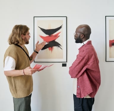 Two men in an art gallery. One, holding a leaflet, gestures at an abstract painting as the other listens. Leaflet text: "IT'S A SIGN TO LEAVE YOU FEELING DRAINED, EXHAUSTED, WORN OUT?"