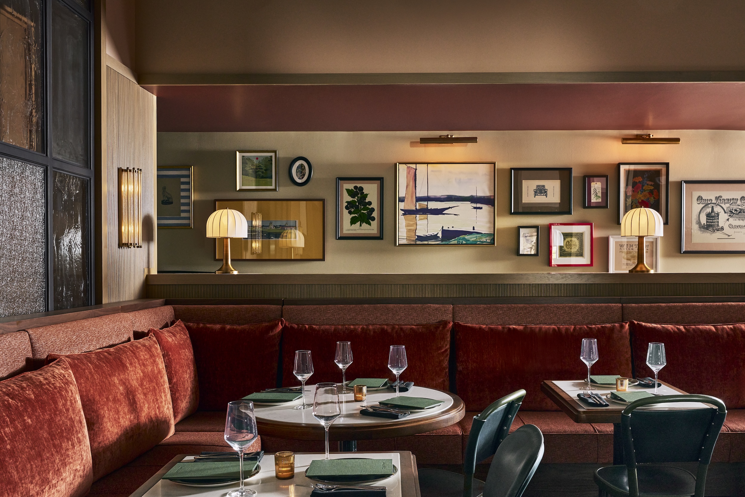 A dining area with red velvet booths and round tables set for meals.
