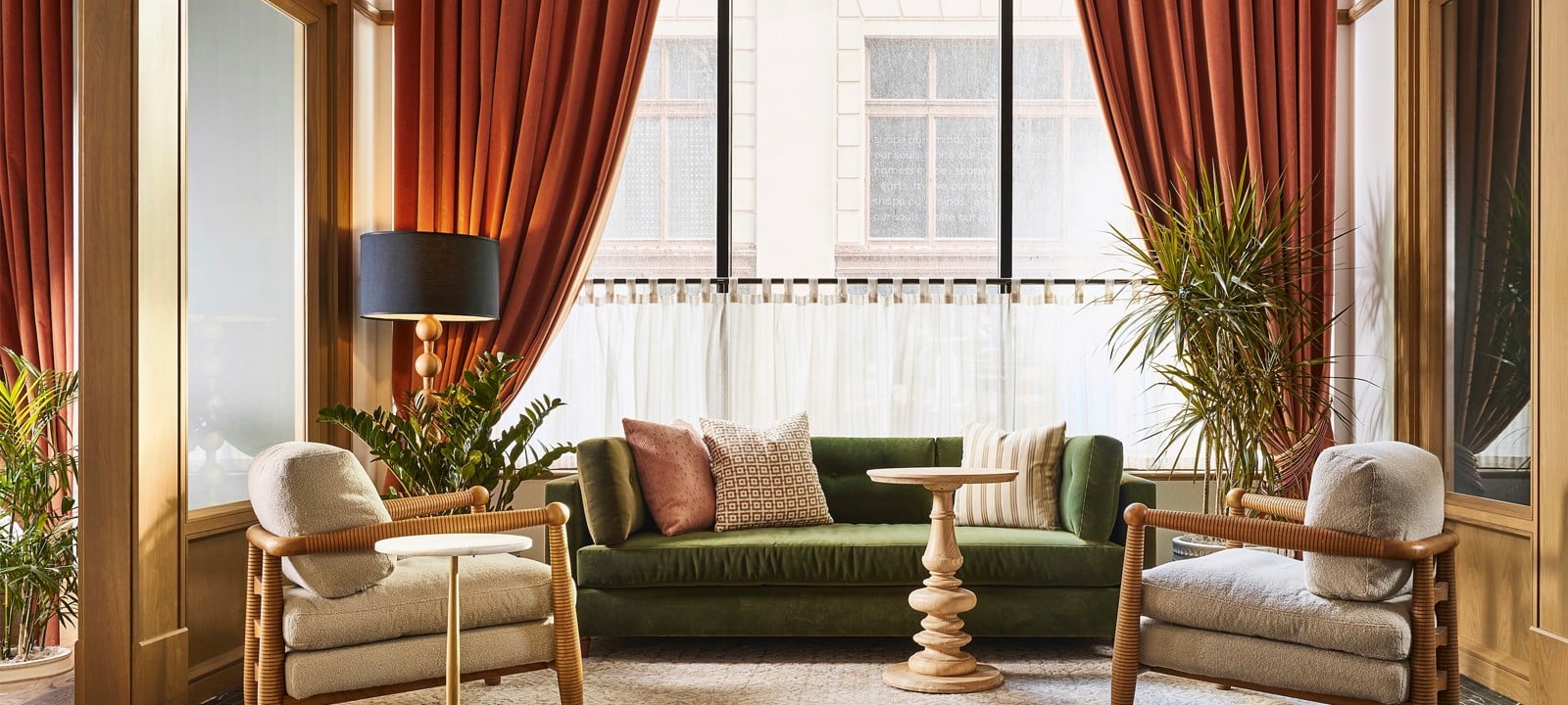 A green velvet sofa and two beige armchairs furnish a lounge area, placed before large windows with orange curtains and sheer drapes.

**Text:**
shape out minds. (v.) to get souls out of the mess. (n.) a shape for souls to get out of the mess. shape out minds. (v.) to get souls out of the mess. (n.) a shape