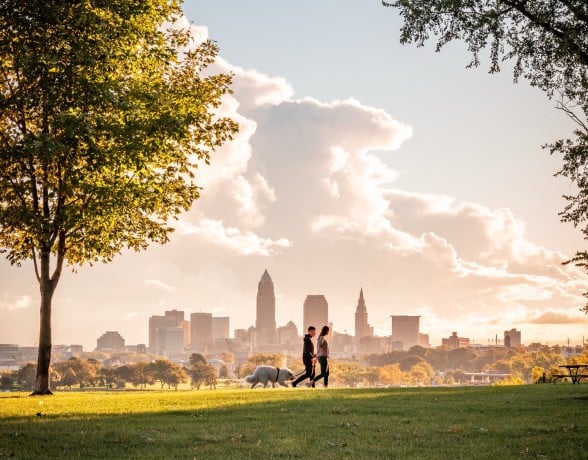 A joyful couple walking their dog in Cleveland, surrounded by beautiful scenery