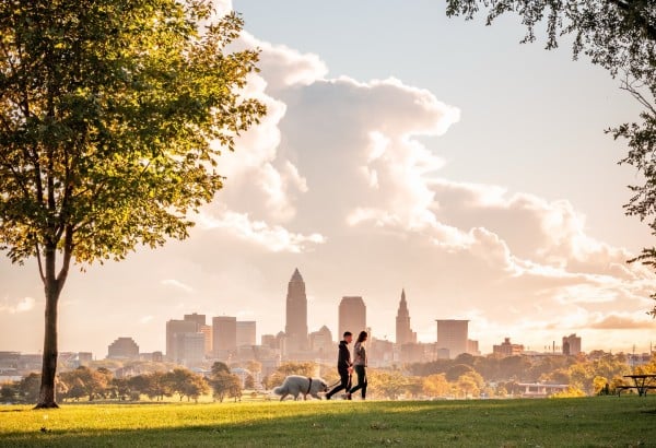 A joyful couple walking their dog in Cleveland, surrounded by beautiful scenery