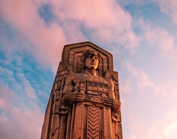 A statue is prominently displayed in front of a grand building, blending art with the architectural backdrop.