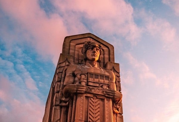 A statue is prominently displayed in front of a grand building, blending art with the architectural backdrop.
