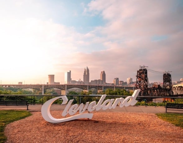Cleveland skyline with the iconic "Cleveland" sign in the foreground, showcasing the city's urban landscape.