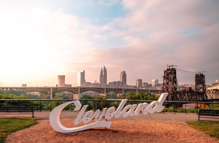 Cleveland skyline with the iconic "Cleveland" sign in the foreground, showcasing the city's urban landscape.