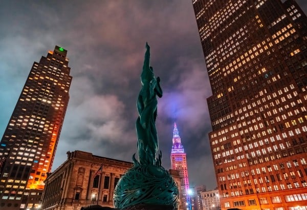 Nighttime city skyline with green statue.