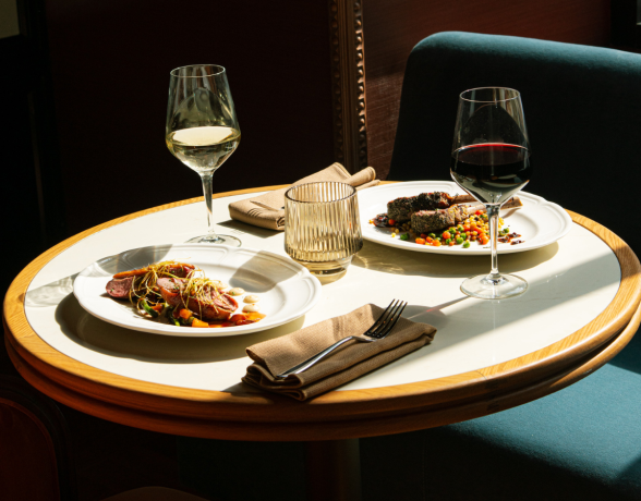 Dinner table at Gwynne with two dishes and a glass of red and white wine.