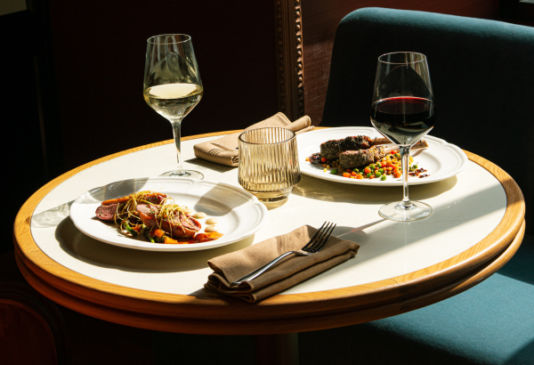 Dinner table at Gwynne with two dishes and a glass of red and white wine.